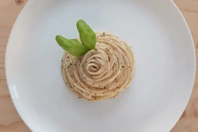 Spaghetti mit Knoblauch, Zwiebeln, Walnüssen und gehobeltem Parmesan, ein herzhaftes, ayurvedisch inspiriertes Gericht.